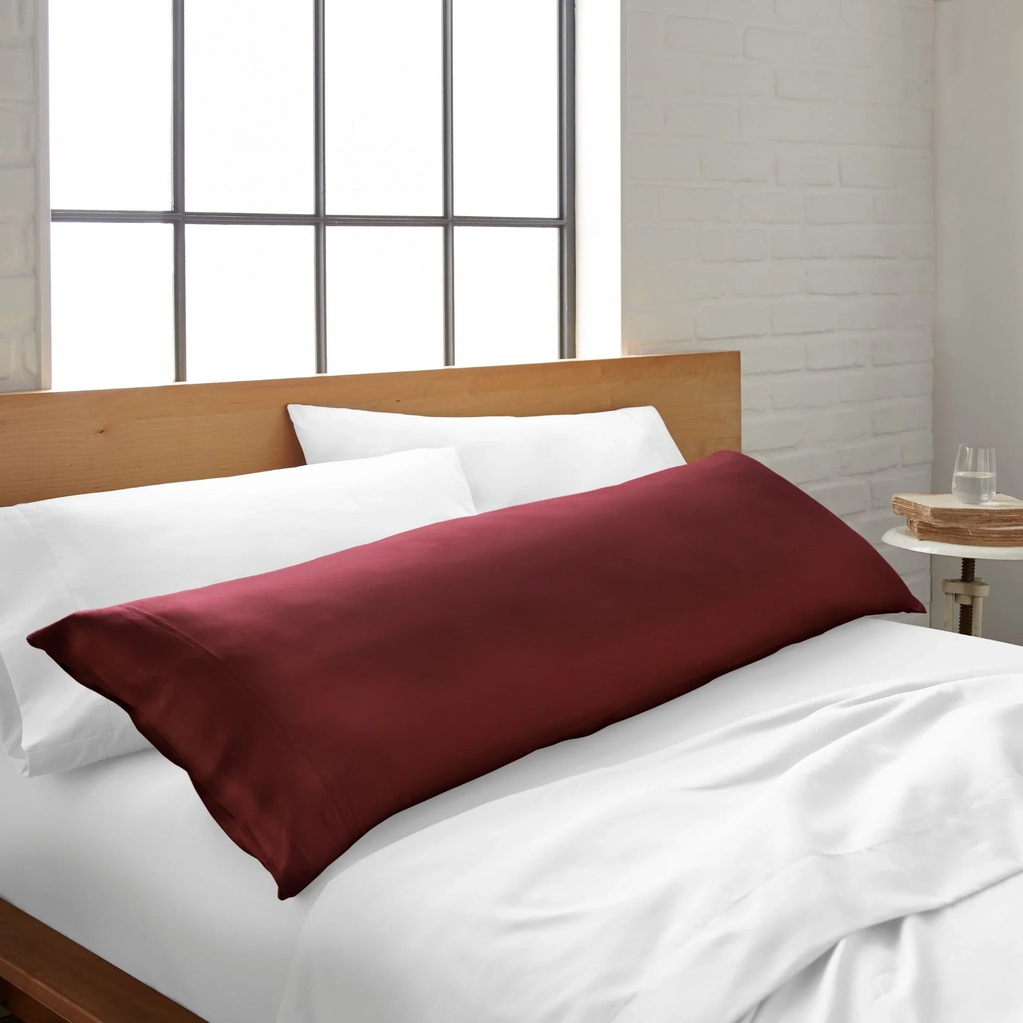 Ruby-red cooling bamboo body pillowcase from Bamboo is Better on a bed, showcasing soft, breathable bamboo fabric for comfortable sleep.